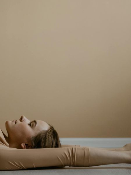 Woman in a calm yoga pose on a powder linen background with soft blur.